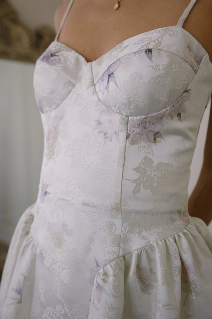 Woman wearing a white floral dress with spaghetti straps and sweetheart neckline.
