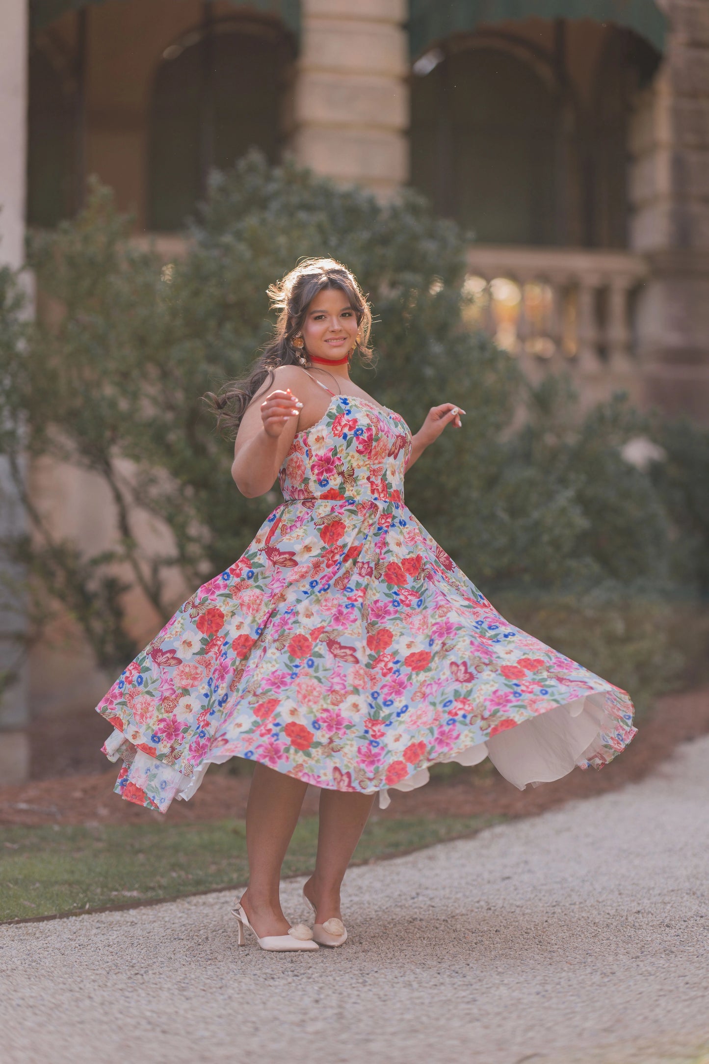 The image shows a woman in a colorful dress walking down a street, with a building and trees in the background. She is wearing footwear, suggesting she is ready to take on the world.
