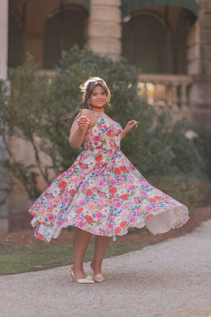 The image shows a woman in a colorful dress walking down a street, with a building and trees in the background. She is wearing footwear, suggesting she is ready to take on the world.